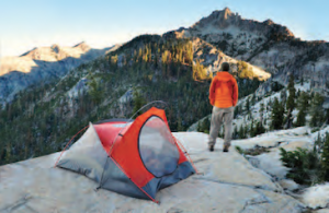 Man outside a tent looking at the mountains
